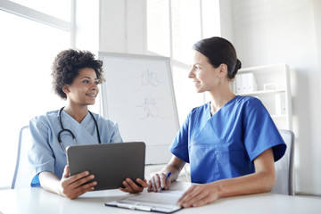 Obraz premium happy doctors with tablet pc meeting at hospital