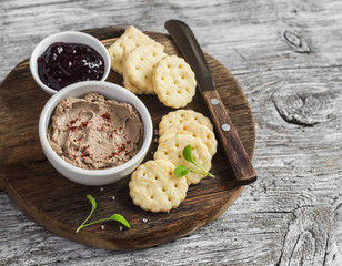 Homemade chicken liver pate, cranberry sauce and homemade cheese biscuits. Delicious snack or appetizer with wine. On light wooden rustic background