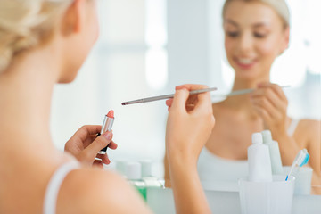 woman with lipstick and make up brush at bathroom