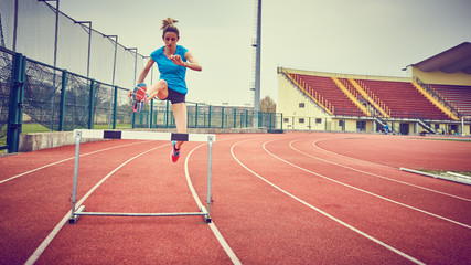 ragazza atletica salta ostacolo in pista