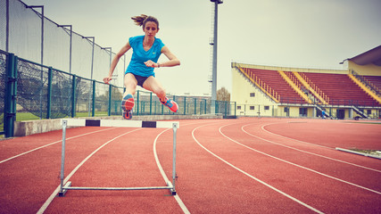 ragazza atletica salta ostacolo in pista
