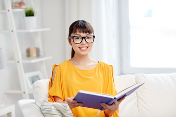 smiling young asian woman reading book at home