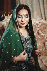 beautiful brunette woman in a traditional ethnic Indian green sari with a scarf on her head