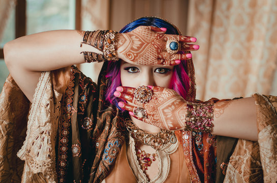 portrait of a beautiful young woman in traditional Indian ethnic dress and painted ational patterns on the hands, mehendi