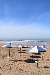 Sonnenschirme werfen kreisrunde Schatten auf den leeren Sandstrand am Atlantik