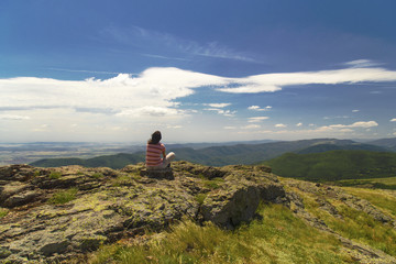 Young woman relaxing on the rocks in high mountain