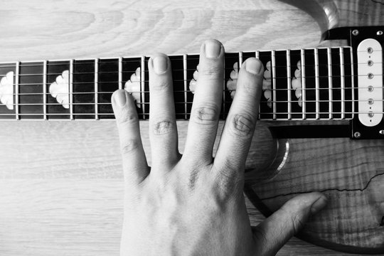 hand of man on an electric guitar - black and white filter
