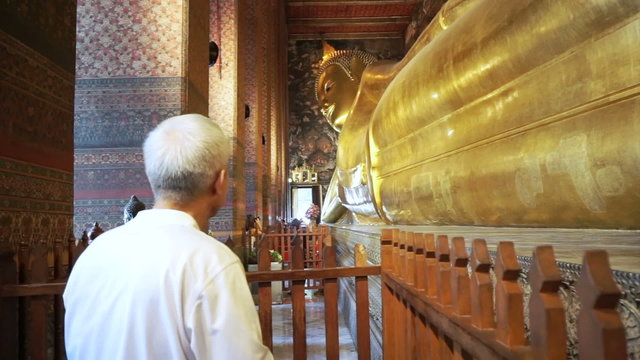 Asian man senior tourist visit Sleeping Buddha, Reclining Buddha statue in Wat Pho of Bangkok, Thailand