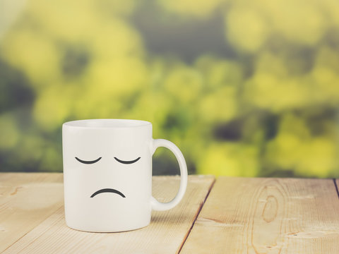 Sad coffee cup on wood table; bokeh green background; vintage co
