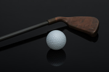 Golf club and ball on black background