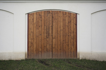 Big wooden barn gate. Monumental farm door, two timber leaf, closed brown gateway with planks and nails. Exterior country situation. Rural entry architecture element. Village foundation background.