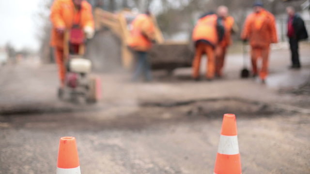 Road workers repair the road,  cones in  foreground