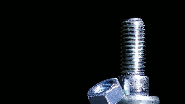 Nut and bolt  rotates  against  dark background. 4K   right side