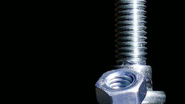 Nut and bolt  rotates  against  dark background. 4K   macro
