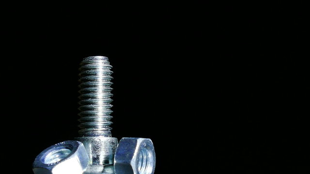 Three Nuts and bolt  rotates  against  dark background. 4K   macro