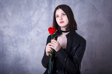 teen girl on a dark background in leather jacket with red roses