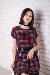 teen girl in a checkered dress posing on a light background