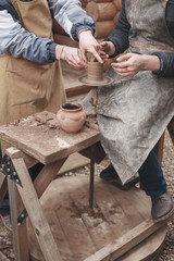 The hands of potter help make  pitcher on  pottery wheel