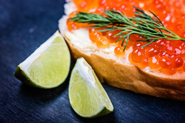 Close up of  bread with butter and red caviar with lime