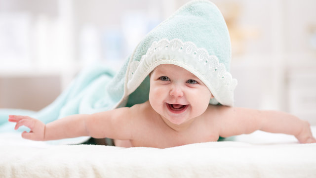 Smiling baby girl after shower with towel on head