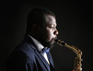 Obraz na płótnie Canvas African American jazz musician playing the saxophone on grey background
