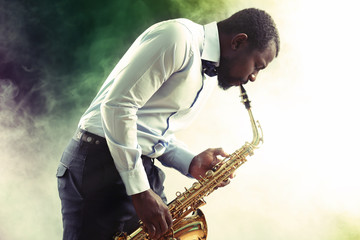 African American jazz musician playing the saxophone against smoky background
