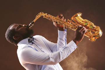 Fototapeta na wymiar African American jazz musician playing the saxophone against smoky background
