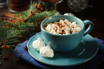 Mug of hot chocolate with marshmallows, fir tree branch on wooden background