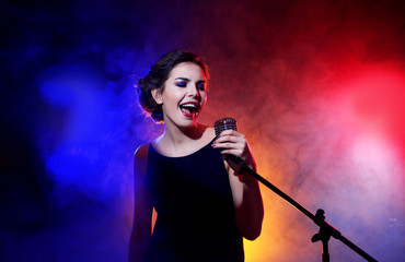 Young beautiful woman singing in colourful smoke, close up