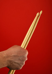 Man hand with two drumsticks over red