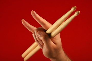 Man hand with drumsticks and devil horns over red