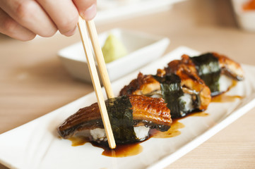 Hand chopsticks Anago or Unagi sushi with japanese sauce