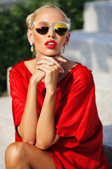 Fashion portrait of young pretty blonde girl in red dress and su