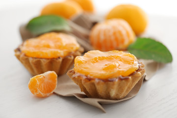 Sweet cakes with tangerines on table, close up