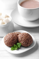 Cup of cocoa with chocolate chip cookies and mint on light background
