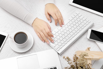 Concept of using electronics. Businesswoman works at office. Computer, laptop, tablet, cup of coffee and other things on the table. Top view