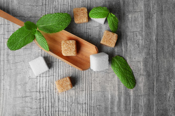 Pile of brown sugar cubes and stevia  on grey wooden background