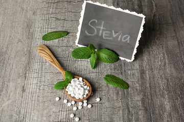 Obraz na płótnie Canvas Analogue of sugar cubes and stevia on grey wooden background