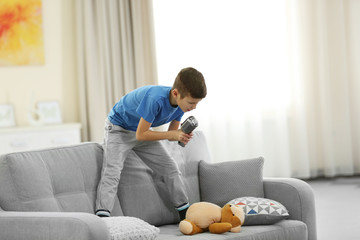 Little boy singing with microphone on a sofa at home