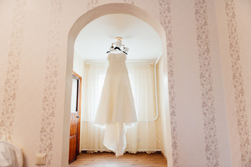 Beautiful White Wedding Gown Hanging by Window