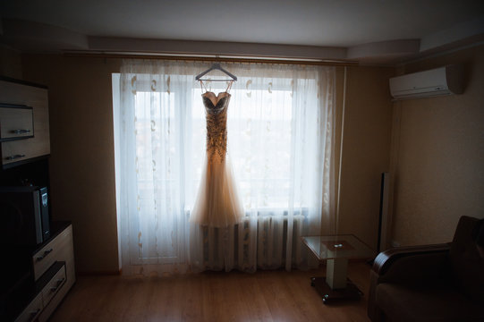 Beautiful White Wedding Gown Hanging by Window