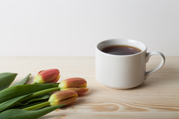 Cup of tea and bunch of spring tulips on the table