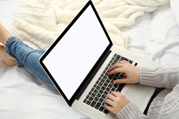 Woman using laptop on her bed