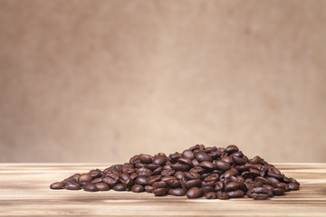 Pile of coffee beans on wooden table opposite a defocused burlap