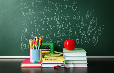 School books on desk near chalkboard