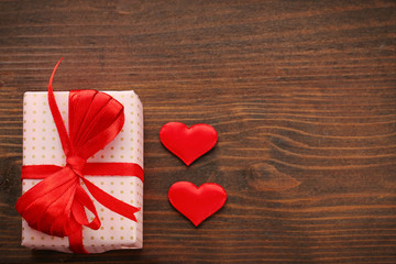 Fototapeta na wymiar Gift box and decorative hearts on wooden background