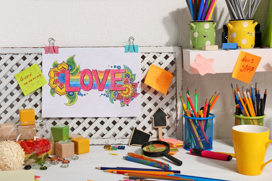 Designer workplace with bright picture, crayons and other things