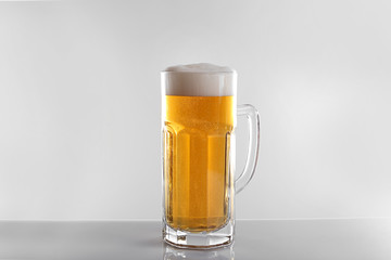 Glass of lager beer on light grey background