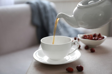 Pouring rose hip tea into cup, home atmosphere