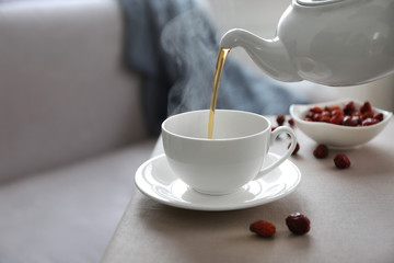 Pouring rose hip tea into cup, home atmosphere